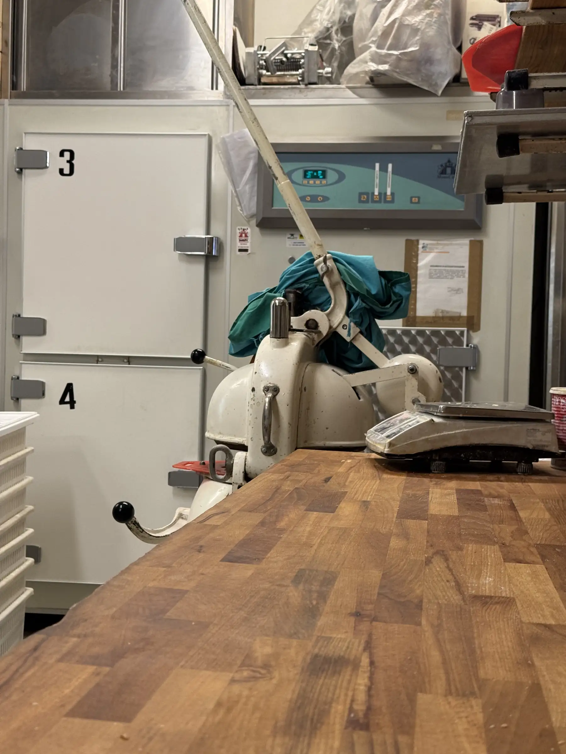 Il banco di legno del laboratorio con la spezzatrice e la bilancia, davanti alle celle di lievitazione