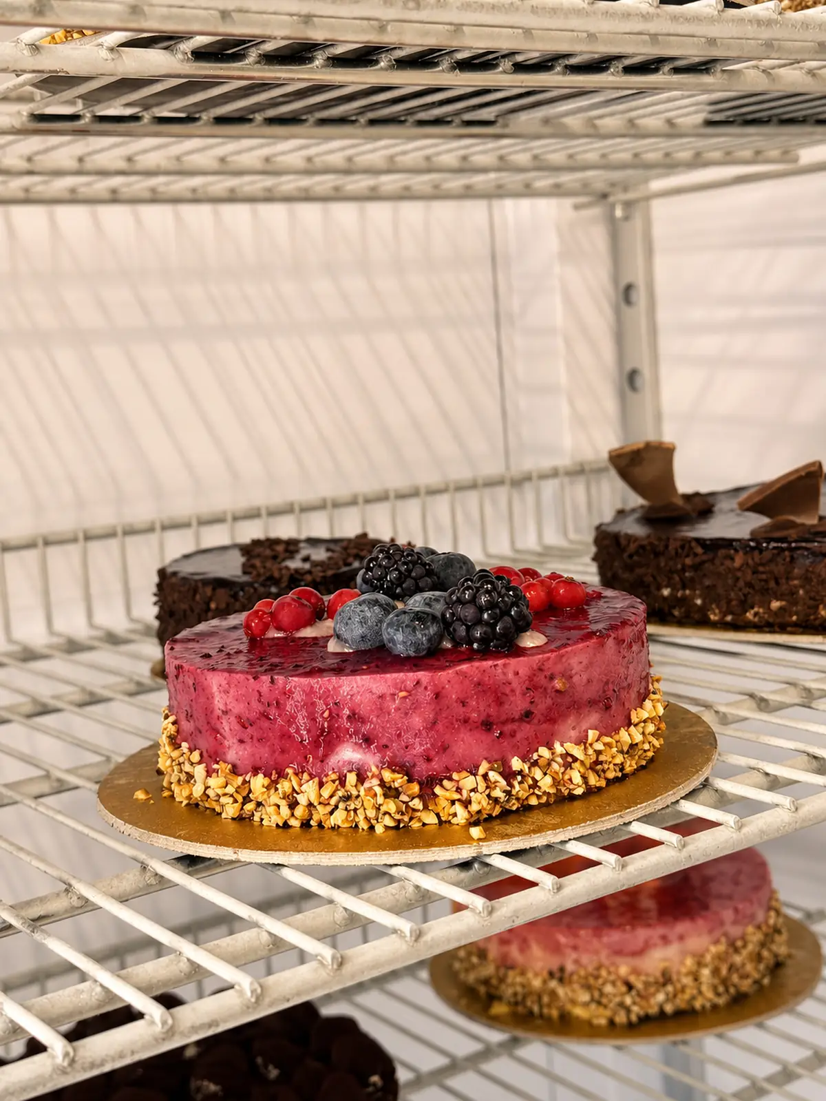 Torta ai frutti di bosco con lamponi e more, sulla griglia della vetrina refrigerata