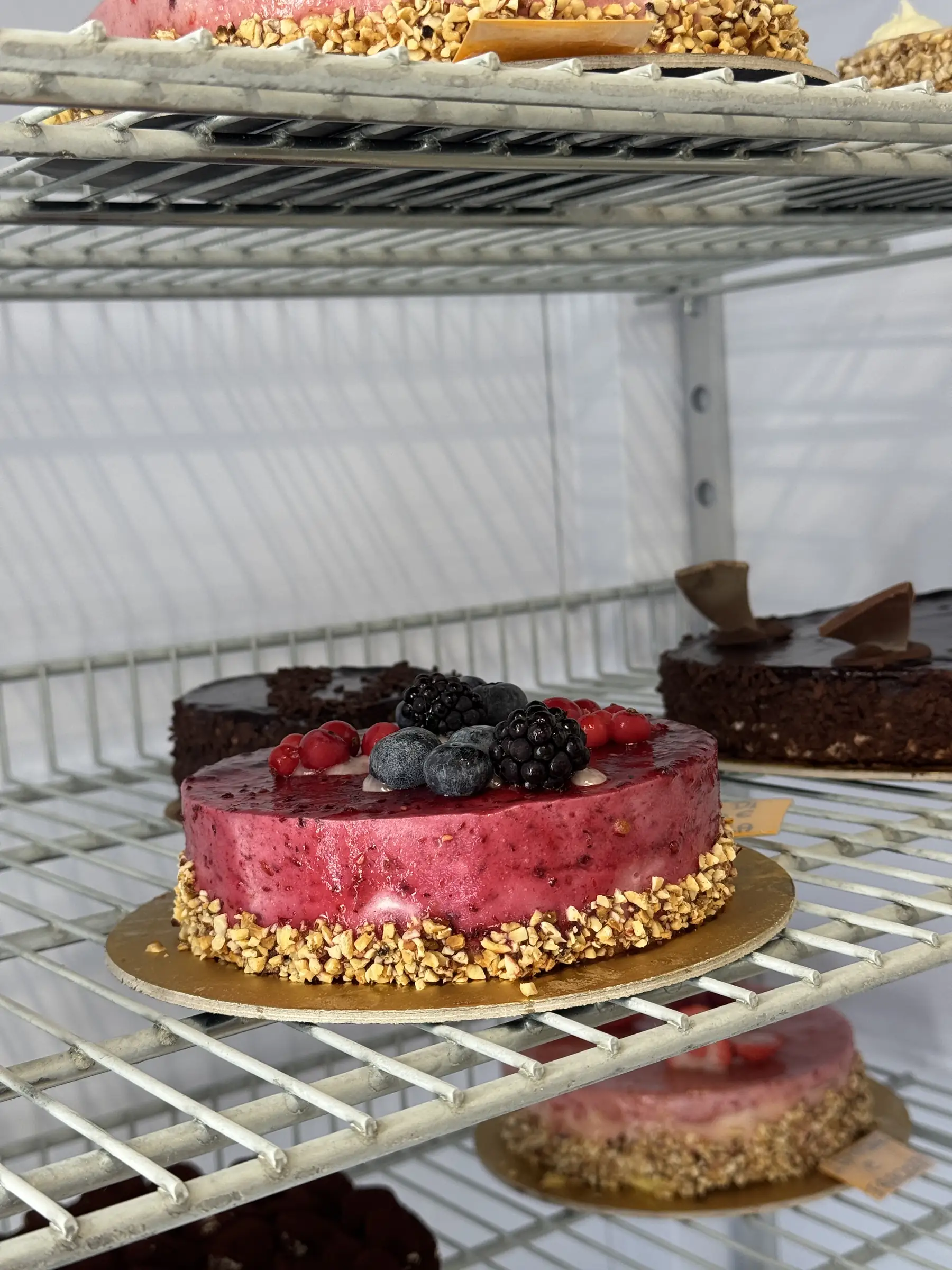 Torta ai frutti di bosco con lamponi e more, sulla griglia della vetrina refrigerata