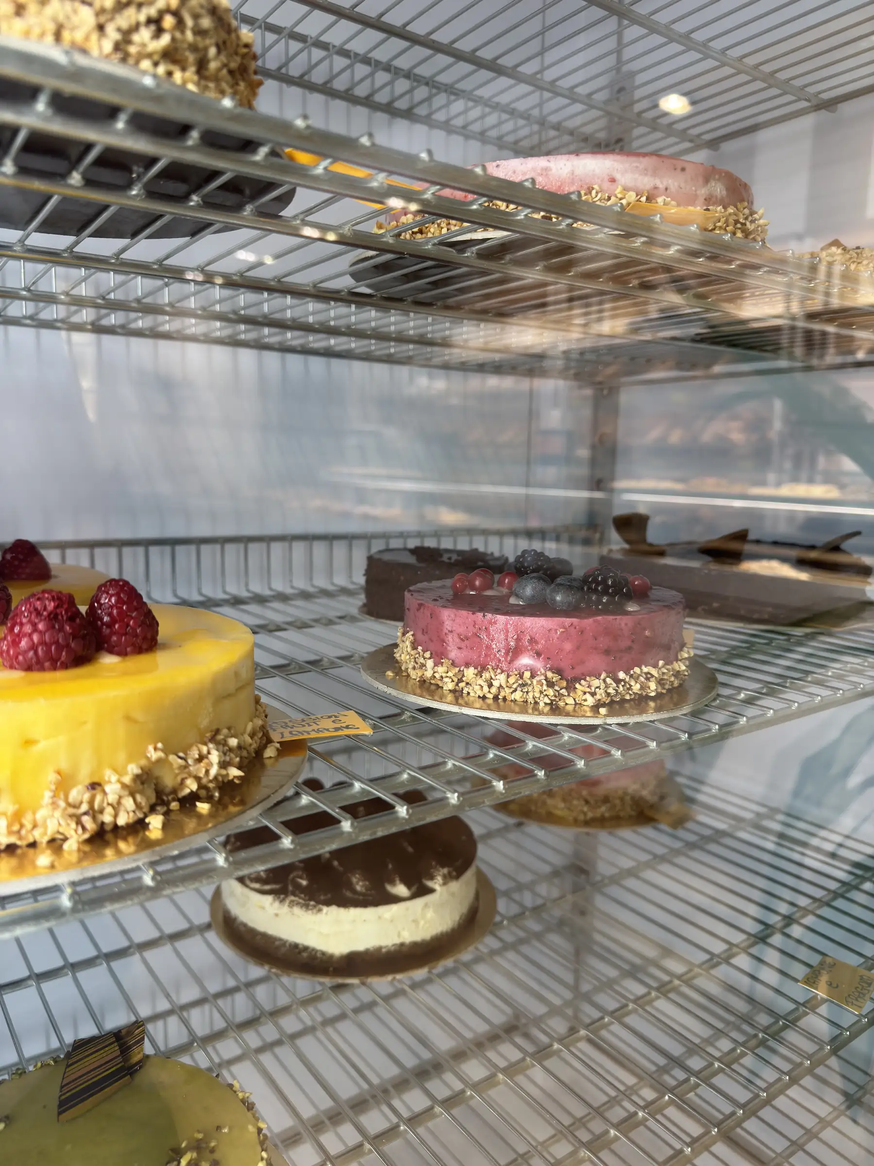 Torte alla frutta e classiche allineate nella vetrina refrigerata del negozio